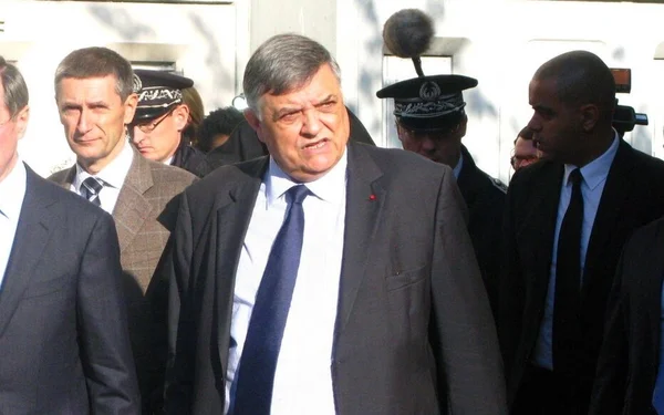Christian Lambert escorté par des agents de sécurité lors d'un déplacement.