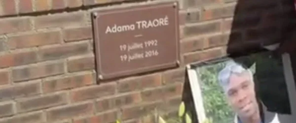 Plaque et portrait d'Adama Traoré, photographie de faible résolution.