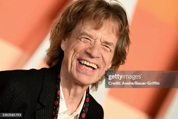 Mick Jagger riant lors d'un événement, photographié avec filigrane.