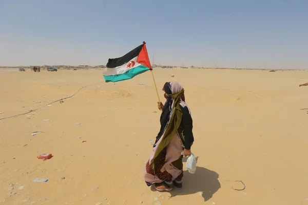 Manifestant portant le drapeau sahraoui dans le désert.
