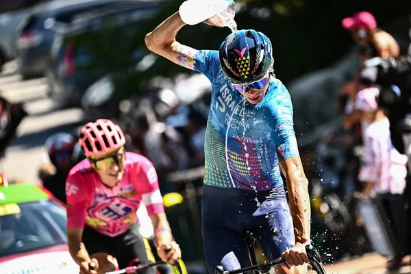 Un coureur de l'équipe Israel-Premier Tech se rafraîchit en versant de l'eau sur son casque pendant une étape caniculaire.