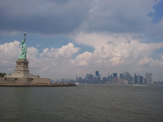 La statue de la Liberté dans le port de New York, avec la skyline de Manhattan en arrière-plan.