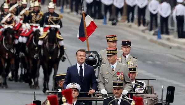 Emmanuel Macron salue la foule lors du défilé du 14 juillet à bord d'un véhicule militaire.