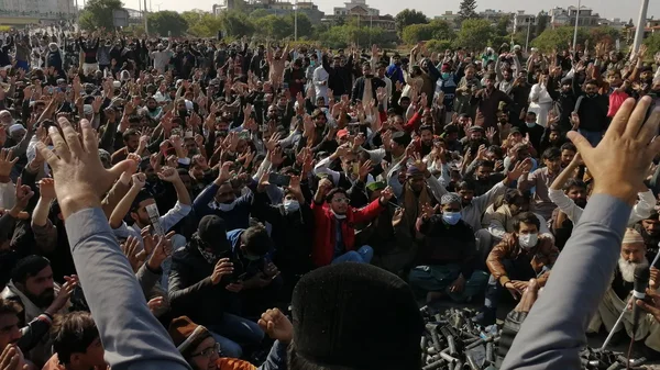 Manifestation publique au Pakistan : une foule nombreuse se rassemble dans les rues, brandissant des téléphones et des pancartes.