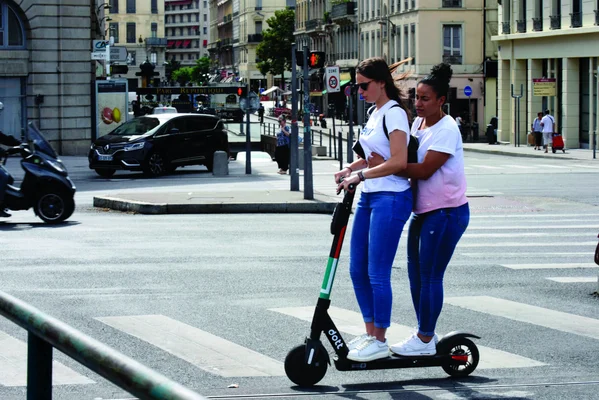 Deux adolescentes partageant une trottinette électrique, une pratique dangereuse qui augmente les risques d'accident.
