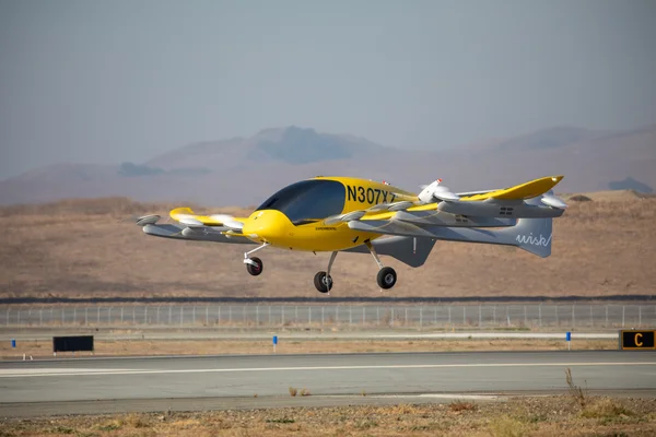Le prototype Wisk Aero Generation 6 en vol, au-dessus d'une piste d'atterrissage.