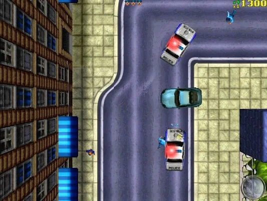In-game screenshot from the original 1997 Grand Theft Auto, showing top-down 2D gameplay with police cars chasing a civilian vehicle in an urban environment. Pixel art style, visible UI elements (score multiplier), and authentic game graphics.