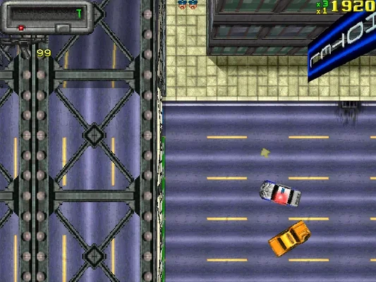 In-game screenshot from Grand Theft Auto (1997), showing top-down 2D pixel art gameplay with cars on a city street and bridge structure, UI elements visible (score, lives).
