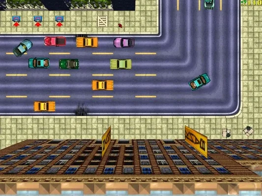 In-game screenshot of Grand Theft Auto (1997) showing top-down 2D gameplay with pixel art cars driving on city streets, sidewalks, and buildings. The image captures the original game's visual style and urban environment.