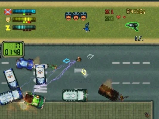 A screenshot from the video game Grand Theft Auto 2 (1999), showing top-down gameplay on a city street with multiple vehicles, including police cars, and a character firing an electric weapon. The user interface is visible at the top of the screen.