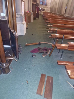 Dégâts à l'intérieur de l'église Saint-Étienne de Mulhouse : bancs brisés et débris au sol.