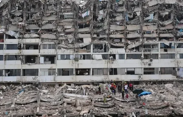 Un immeuble résidentiel effondré, avec des secouristes cherchant des survivants parmi les gravats.