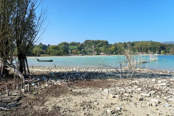 Vue du lac de Paladru, ses eaux turquoise et ses rives rocheuses sous un ciel dégagé.