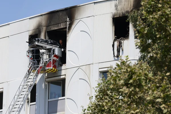 Pompier examinant les dégâts après l'incendie criminel aux Moulins, où sept personnes ont péri.