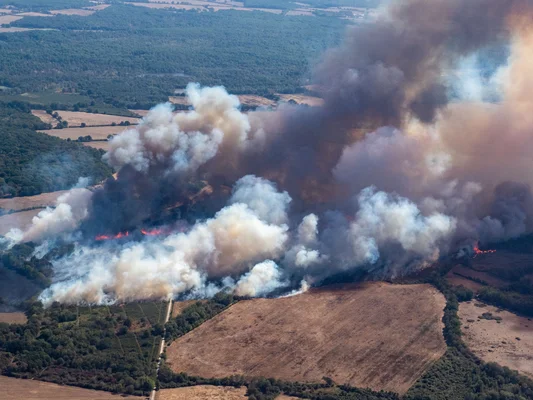 Vue aérienne d'un incendie de forêt dévastant des zones rurales.