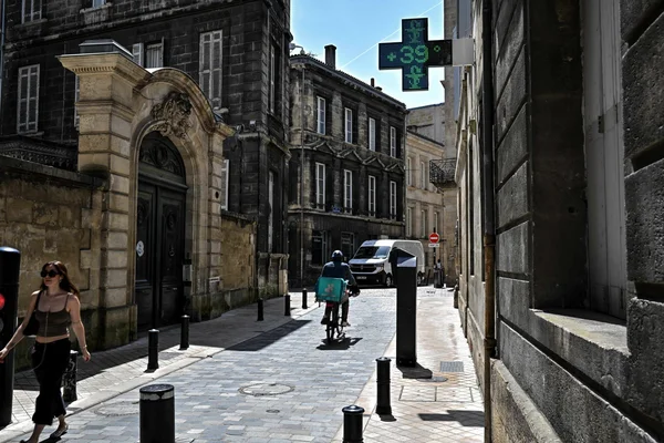 Livreur à vélo dans une rue ensoleillée, avec une pharmacie affichant +39°C.