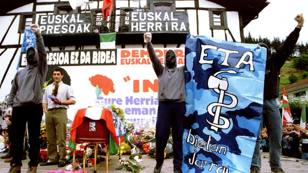Membres d'ETA brandissant une banderole avec le symbole de l'organisation.