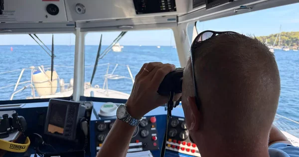 Surveillance en mer au large de Cannes : un agent observe à la jumelle depuis un navire de contrôle.