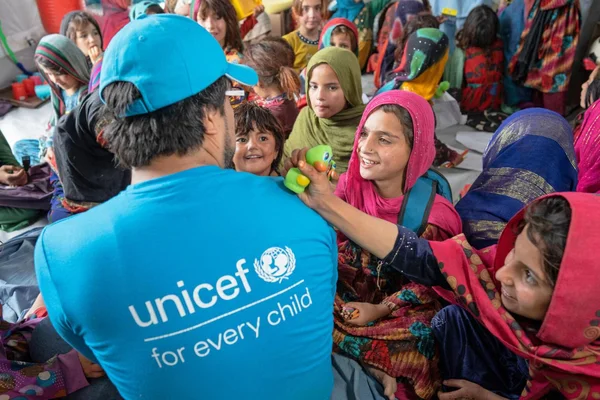 Un agent de l'UNICEF entouré d'enfants souriants lors d'une mission sur le terrain.