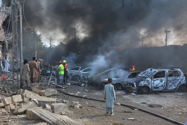 Conséquences de l'attaque à l'explosif d'un train au Pakistan : véhicules détruits et intervention des secours.