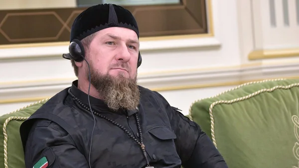 Ramzan Kadyrov, dirigeant tchétchène, assis sur un canapé vert avec un casque et une veste tactique.