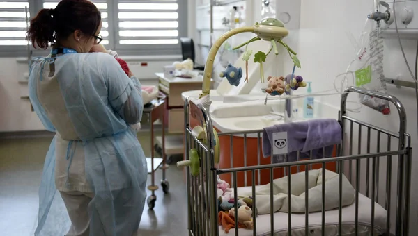 Un soignant tient un nouveau-né dans une maternité, illustrant la gestion de la canicule par les personnels hospitaliers.
