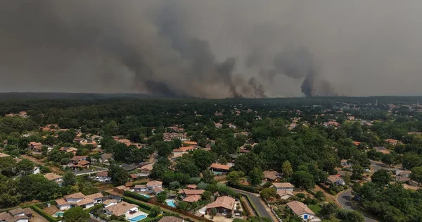 Fumée massive s'élevant au-dessus d'un quartier résidentiel menacé par les incendies dans le Sud-Ouest.