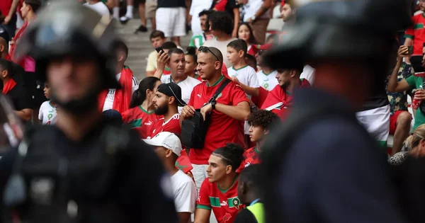 Supporters marocains dans les tribunes, surveillés par des policiers en tenue anti-émeute.