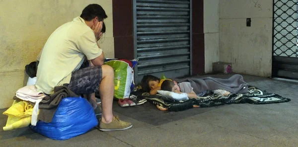 Une famille dormant dans la rue, une scène de sans-abrisme nocturne.