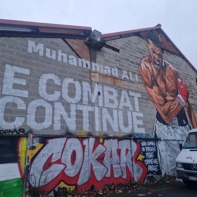 Fresque murale de Muhammad Ali à Ivry-sur-Seine, avec les inscriptions 'Muhammad ALI' et 'LE COMBAT CONTINUE'.