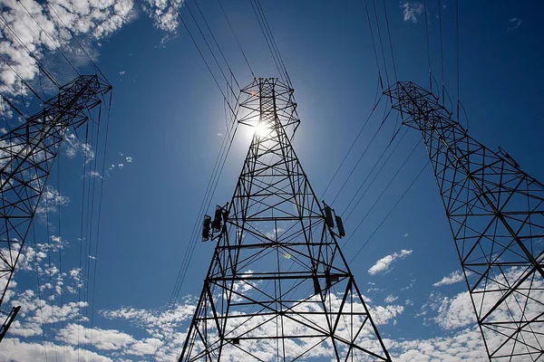 Pylônes à haute tension sous un ciel bleu ensoleillé, illustrant le réseau électrique français.