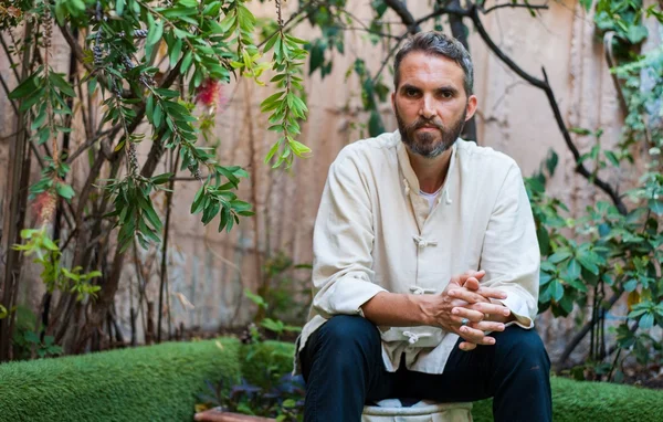 Ludovic Mohamed Zahed, imam et homosexuel, assis sur une haie, regardant l'objectif.