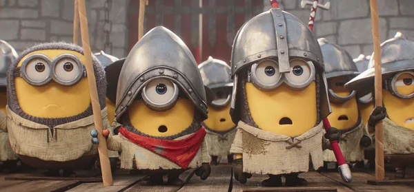 Minions en tenue médiévale dans une cour en pierre : le personnage central au casque à un œil et à l'écharpe rouge affiche une expression surprise.