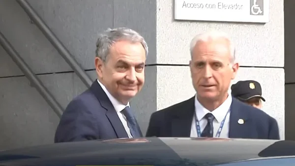 José Luis Zapatero accompagné d'une autre personne devant un bâtiment judiciaire.