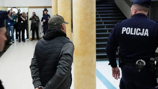 Un suspect ukrainien escorté par la police polonaise lors de son interpellation.