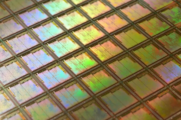 Tranche de silicium avec des puces intégrées aux reflets irisés, représentant la fabrication de semi-conducteurs.