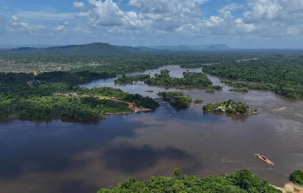 Vue aérienne d'un fleuve guyanais traversant la forêt tropicale, avec un petit bateau en navigation.