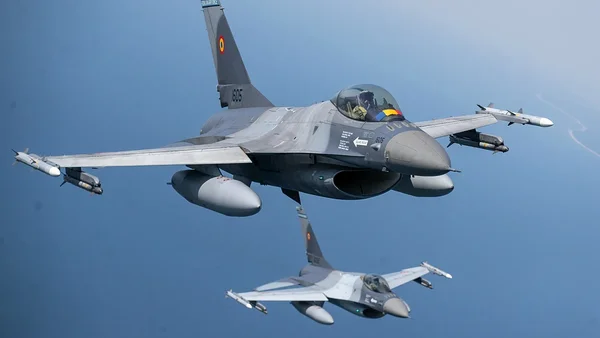 Deux F-16 de l'Armée de l'Air roumaine en vol de formation, avec missiles et réservoirs externes.