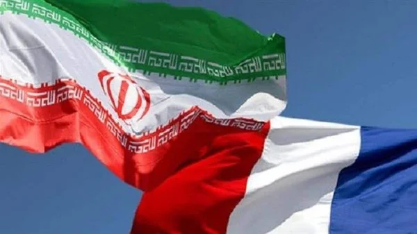Drapeaux iranien et français flottant ensemble, symbole des relations diplomatiques entre les deux pays.