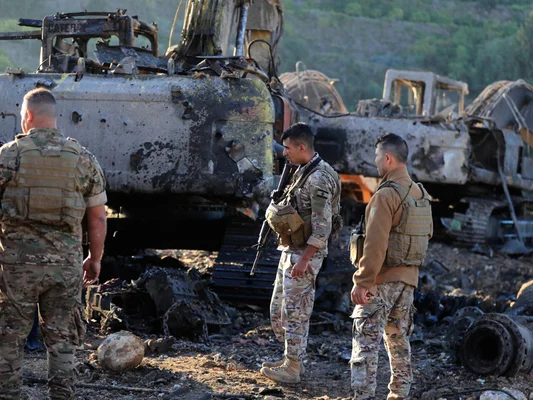 Soldats libanais examinant les restes calcinés d'engins de chantier après une destruction.