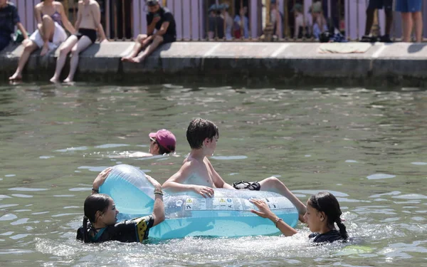 Des enfants se baignent dans le canal Saint-Martin, surveillés depuis la berge.