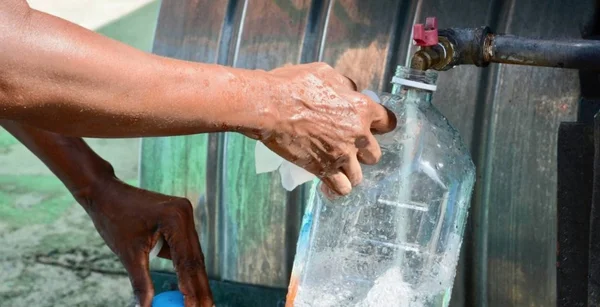 Remplissage d'une bouteille d'eau à un robinet de réservoir, symbole du rationnement d'urgence à Porto Rico.