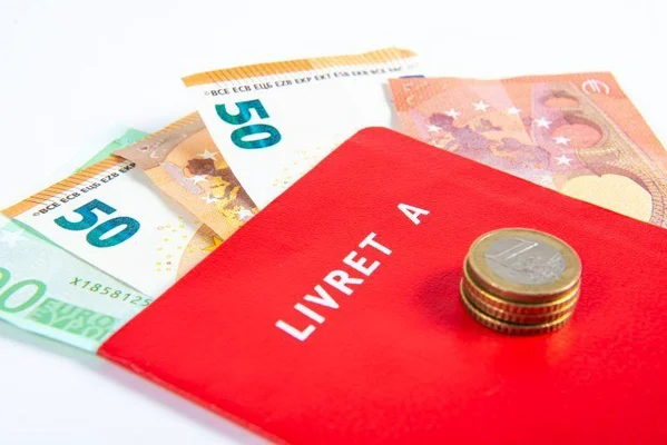Livret A rouge avec pièces et billets en euros.