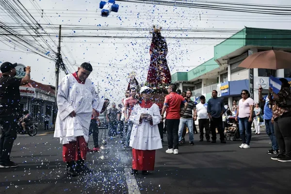 Procession religieuse au Nicaragua avec une statue de la Vierge et des confettis bleus.