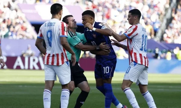 Kylian Mbappé retenu par un officiel lors d'un match.