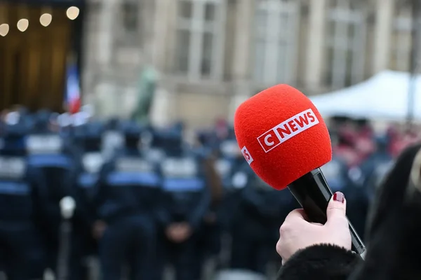 Micro de CNews devant un cordon de police, illustrant les séquences incriminées par l'Arcom.