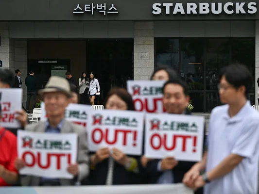 Manifestation devant un Starbucks à Séoul : pancartes 'STARBUCKS OUT!'.