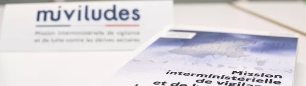 Brochure de la Miviludes présentée sur un panneau.