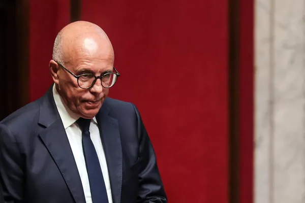 Éric Ciotti en costume sombre, regardant vers le bas.