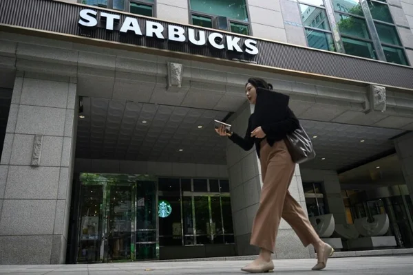 Passante devant un Starbucks à Séoul, regardant son téléphone.